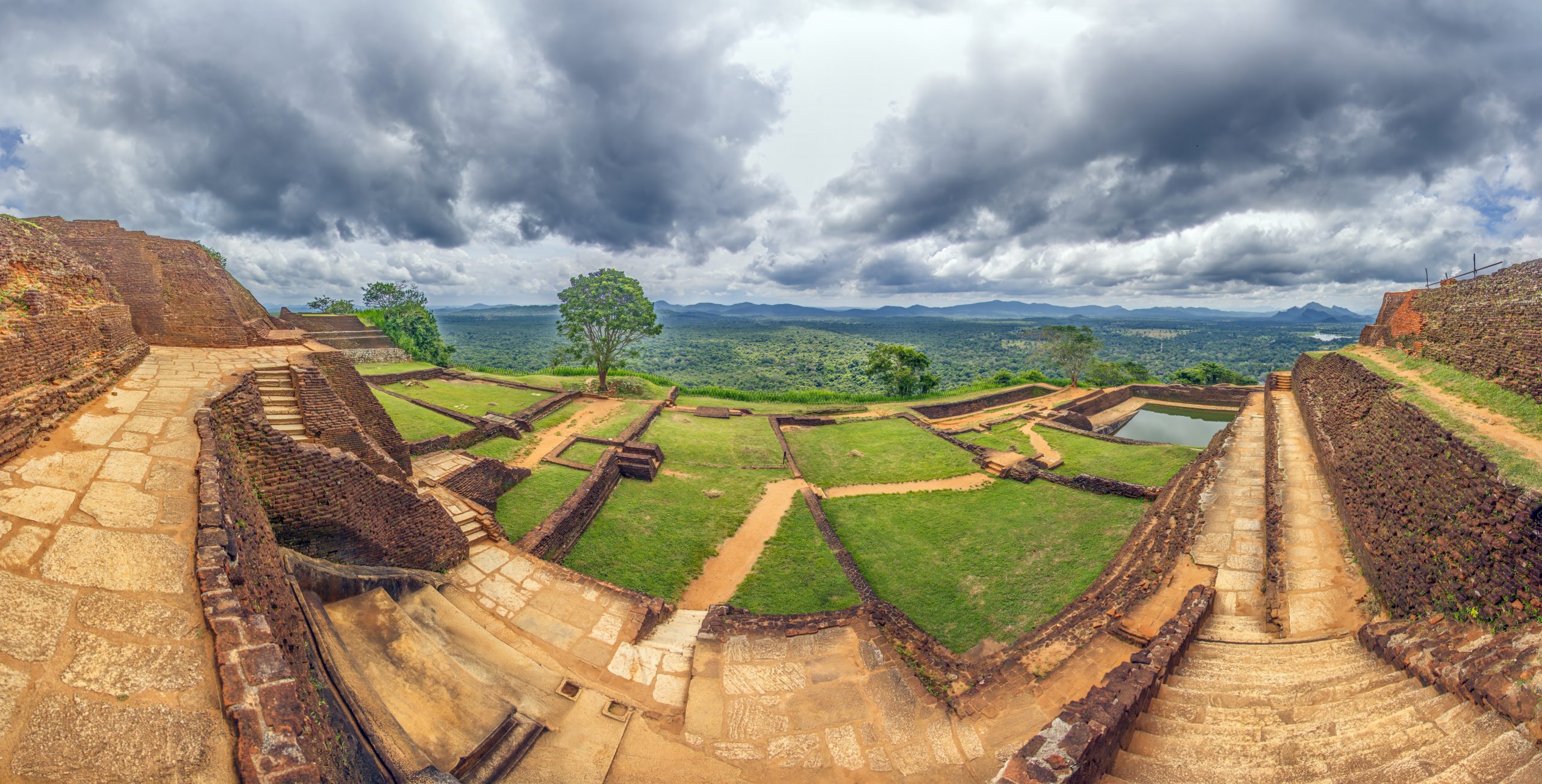 Panorama of ancient ruins on Sigiriya Rock with green landscape and stormy clouds during daytime